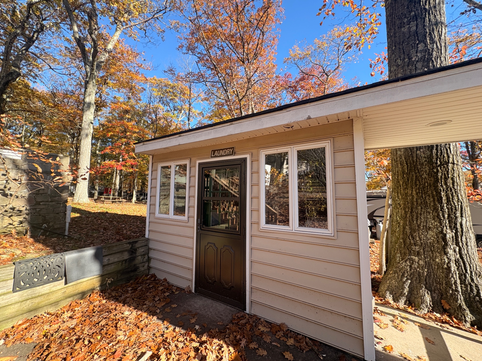 The campground laundry building — a small tan building with a LAUNDRY sign above the door, surrounded by autumn trees
